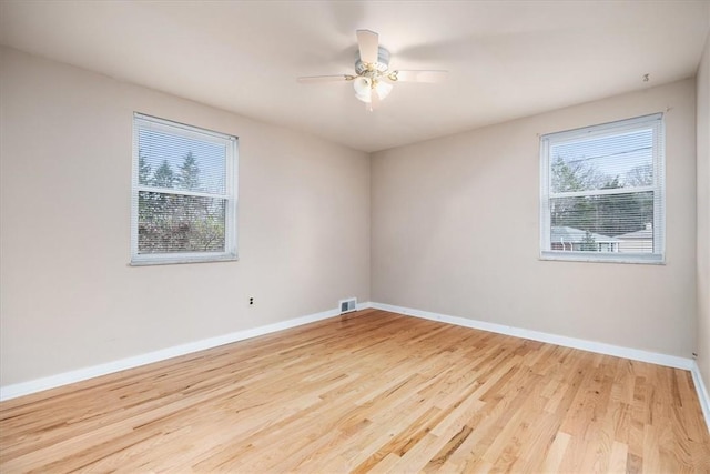 empty room featuring ceiling fan, light hardwood / wood-style flooring, and a healthy amount of sunlight