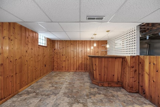 bar featuring wooden walls and a drop ceiling