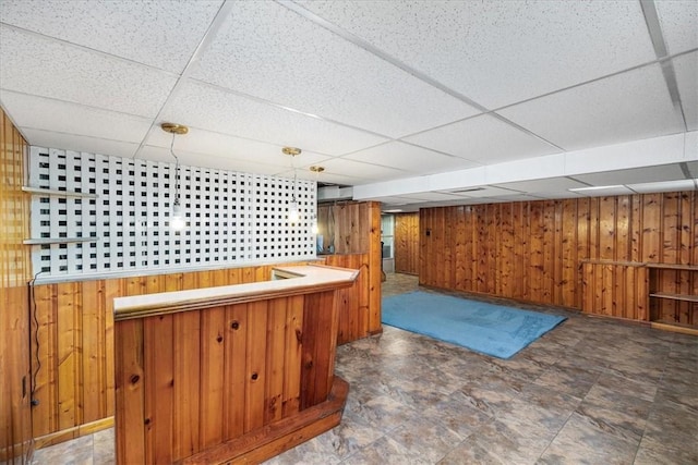 bar with a paneled ceiling, decorative light fixtures, and wooden walls