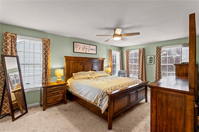 bedroom featuring multiple windows, ceiling fan, and light colored carpet