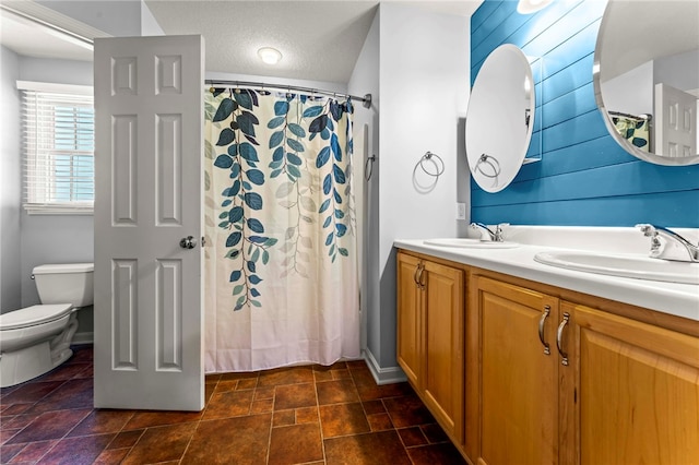 bathroom with a textured ceiling, vanity, toilet, and walk in shower