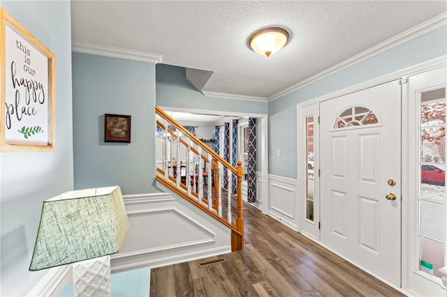 foyer entrance with dark hardwood / wood-style flooring, a textured ceiling, and ornamental molding