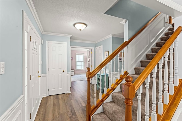 foyer entrance with a textured ceiling, dark hardwood / wood-style floors, and ornamental molding