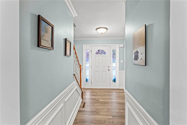 foyer entrance featuring wood-type flooring, a textured ceiling, and ornamental molding