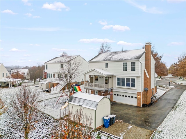 snow covered back of property with a garage