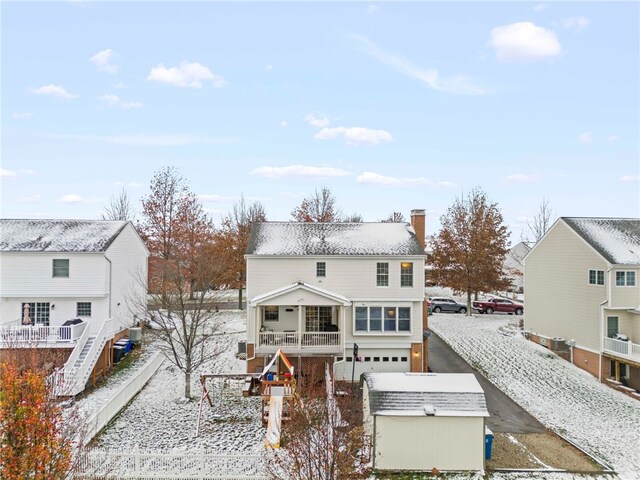 snow covered back of property with a garage