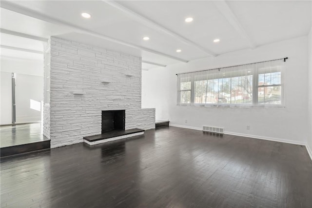 unfurnished living room featuring beamed ceiling, a stone fireplace, and dark wood-type flooring