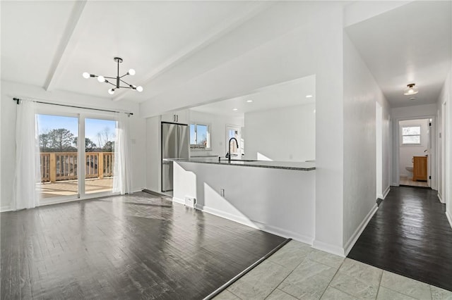 interior space with an inviting chandelier, sink, hanging light fixtures, light hardwood / wood-style floors, and stainless steel refrigerator