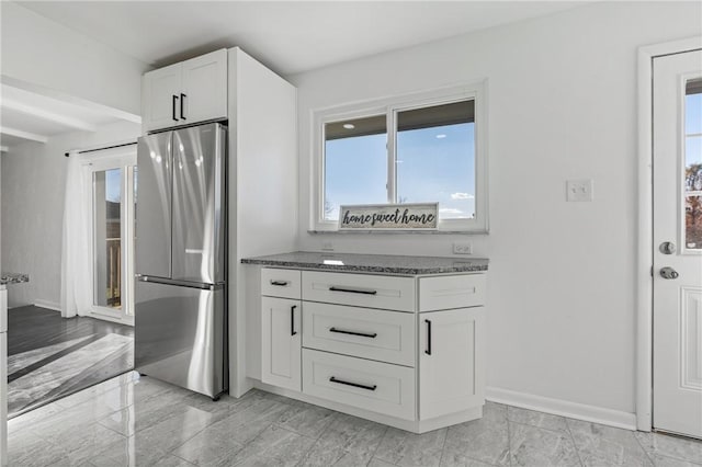 kitchen featuring white cabinets, stainless steel fridge, plenty of natural light, and beam ceiling