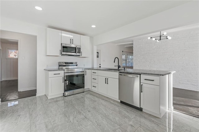 kitchen featuring kitchen peninsula, white cabinetry, sink, and appliances with stainless steel finishes