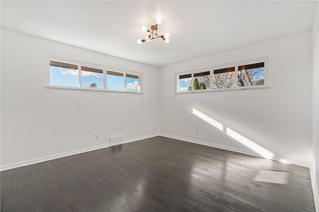 unfurnished room featuring dark hardwood / wood-style floors and an inviting chandelier