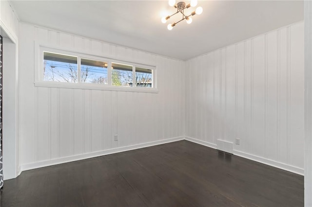 spare room featuring dark hardwood / wood-style flooring and an inviting chandelier