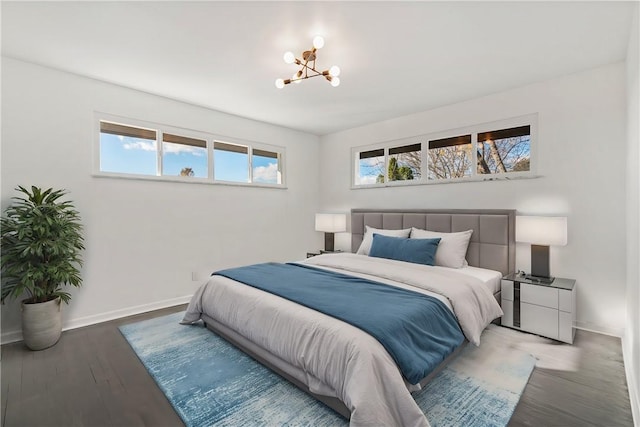 bedroom with hardwood / wood-style floors, a notable chandelier, and multiple windows