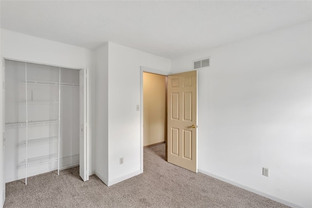 unfurnished bedroom featuring light carpet and a closet