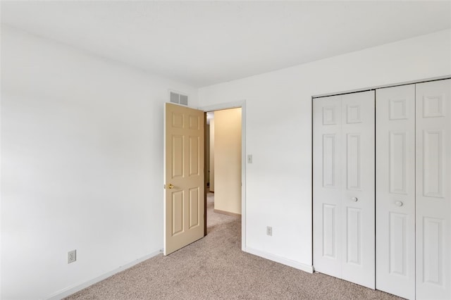 unfurnished bedroom featuring light carpet and a closet