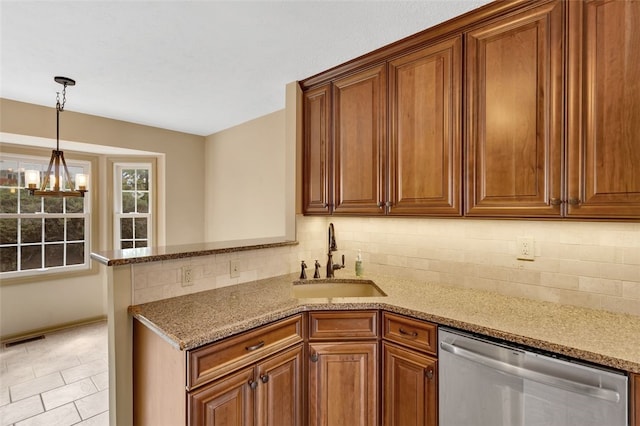 kitchen featuring light stone countertops, dishwasher, sink, backsplash, and a chandelier