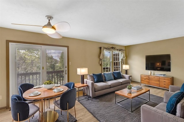 living room with light wood-type flooring, plenty of natural light, and ceiling fan