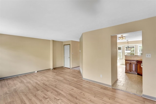 empty room with light hardwood / wood-style floors and an inviting chandelier