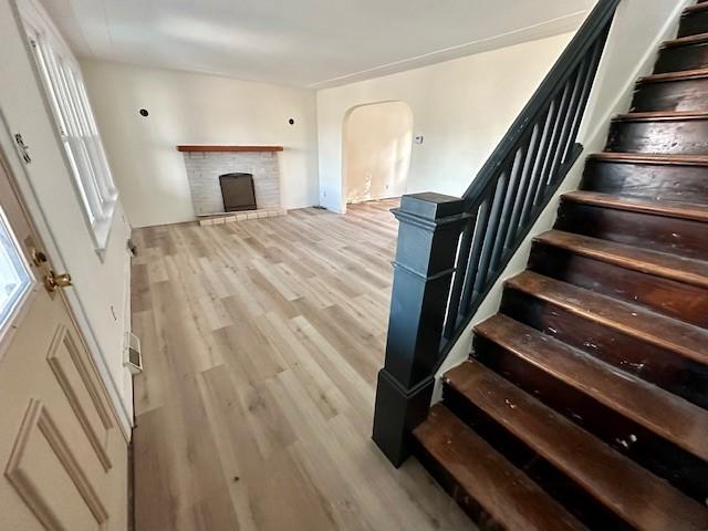 stairway with hardwood / wood-style floors and a fireplace