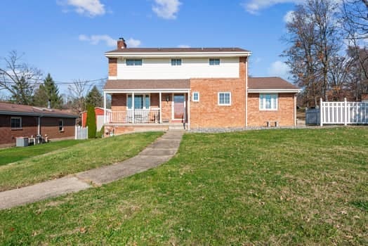 rear view of house featuring a yard and covered porch