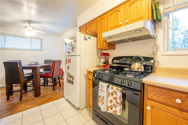 kitchen featuring light hardwood / wood-style floors, ceiling fan, white fridge, and black range with gas cooktop