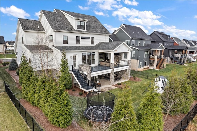 back of house featuring a trampoline, a deck, and a lawn