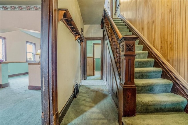 staircase featuring carpet and wooden walls