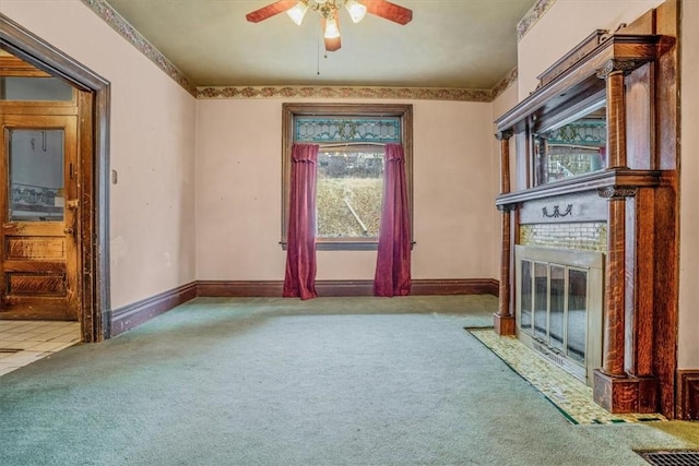 unfurnished living room featuring a fireplace, ceiling fan, and light carpet