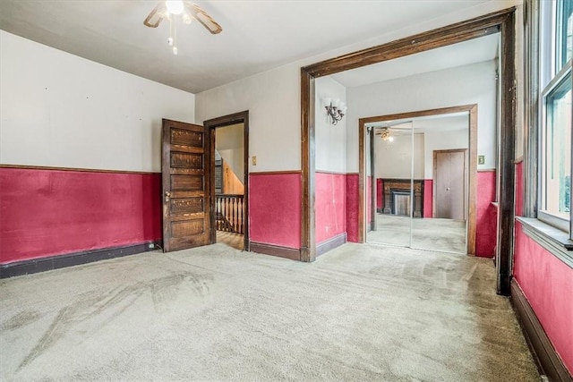 unfurnished room featuring carpet, ceiling fan, and a fireplace