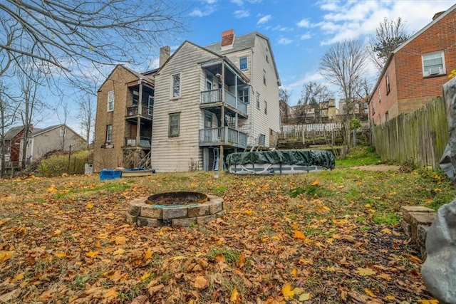 back of house featuring a balcony, a fire pit, and a covered pool