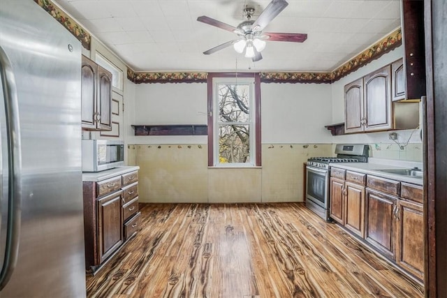 kitchen featuring ceiling fan, hardwood / wood-style floors, dark brown cabinets, and appliances with stainless steel finishes