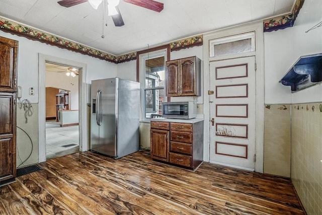 kitchen with dark hardwood / wood-style flooring, stainless steel appliances, and tile walls