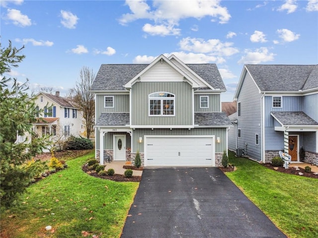 view of front of home with a garage, a front lawn, and central air condition unit