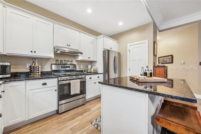 kitchen with light hardwood / wood-style flooring, dark stone countertops, appliances with stainless steel finishes, white cabinets, and ornamental molding