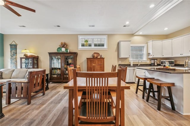 dining room featuring ceiling fan, sink, ornamental molding, and light wood-type flooring