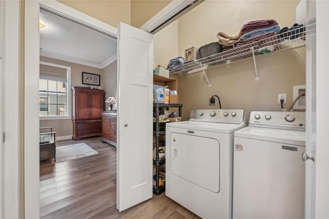 laundry room with wood-type flooring, ornamental molding, and washing machine and clothes dryer