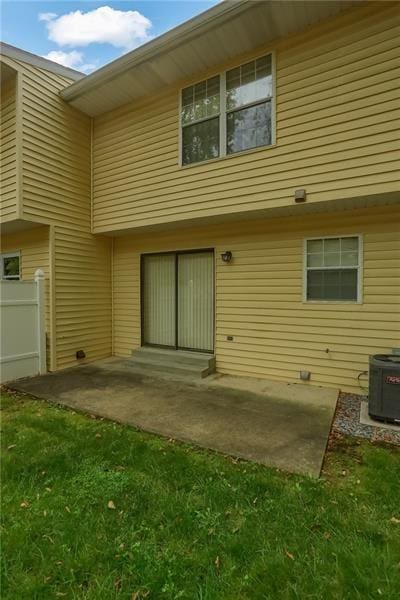 rear view of property featuring a lawn, cooling unit, and a patio area