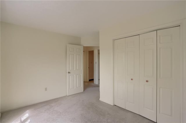 unfurnished bedroom featuring light carpet and a closet