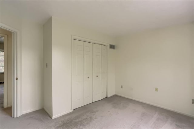 unfurnished bedroom with light colored carpet and a closet