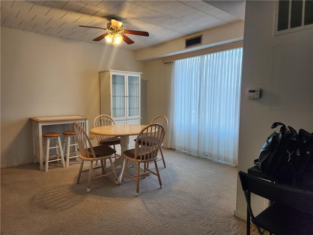 carpeted dining room with ceiling fan