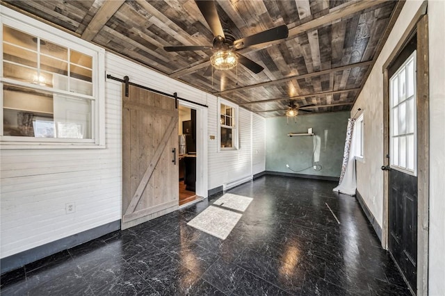 spare room featuring a barn door, ceiling fan, wooden walls, and wood ceiling