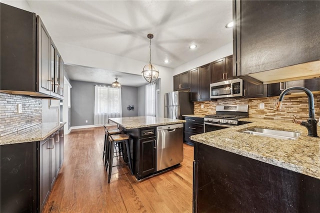 kitchen featuring pendant lighting, a center island, sink, light hardwood / wood-style floors, and stainless steel appliances