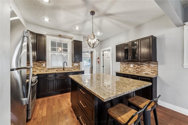 kitchen with appliances with stainless steel finishes, light wood-type flooring, backsplash, pendant lighting, and a center island