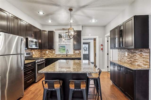 kitchen with light wood-type flooring, appliances with stainless steel finishes, a center island, and pendant lighting