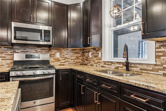 kitchen with decorative backsplash, sink, light stone counters, and stainless steel appliances