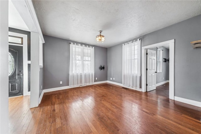 spare room featuring wood-type flooring, a textured ceiling, and a wealth of natural light