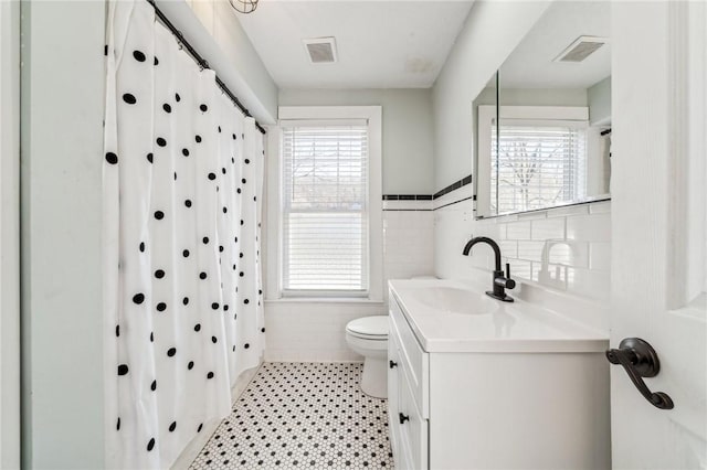 bathroom with vanity, curtained shower, toilet, and tile walls