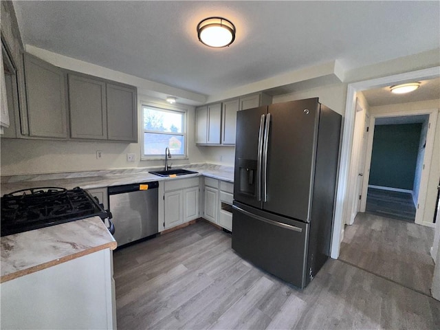 kitchen featuring gray cabinets, light wood-type flooring, sink, and appliances with stainless steel finishes