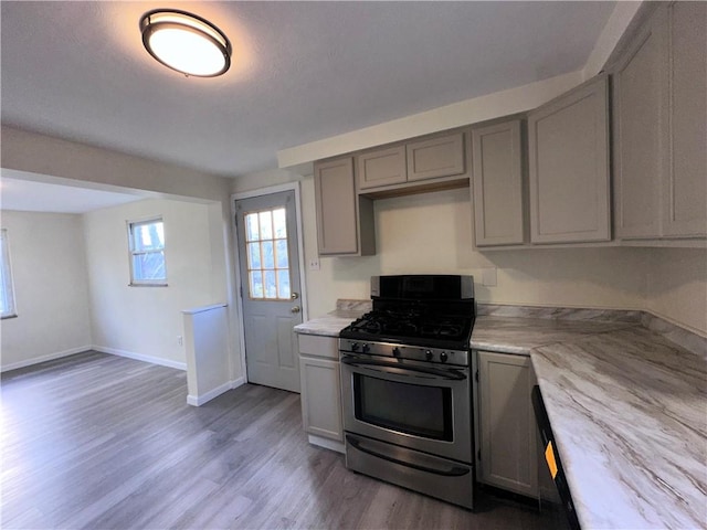 kitchen featuring hardwood / wood-style floors, stainless steel gas range oven, and gray cabinets