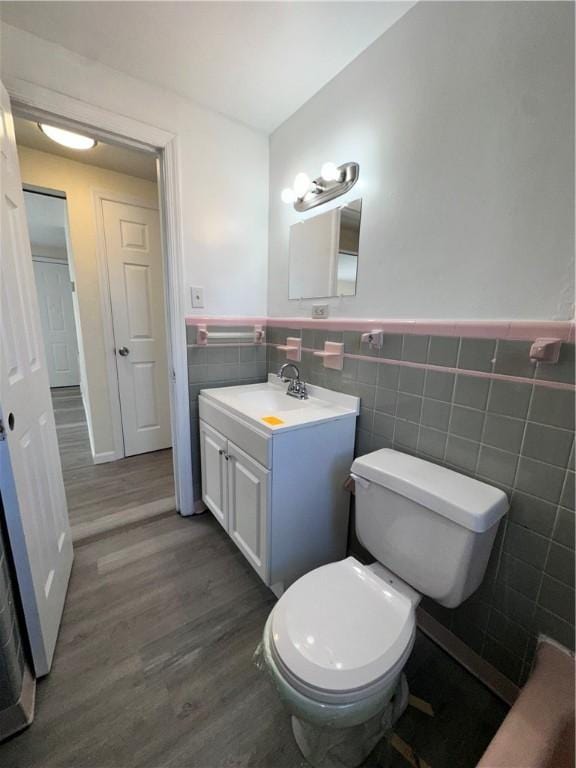 bathroom with hardwood / wood-style floors, vanity, toilet, and tile walls